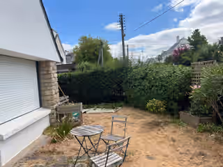 Coin de jardin envahi de végétation contre une maison blanche